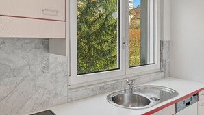 A modern kitchen with a stainless steel sink, a window, and a built-in stove. - Amazing 2BR flat: spacious and central (Duke2) (Zürich)