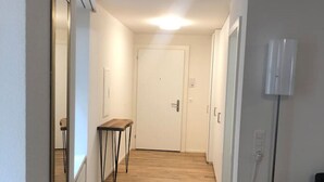 A hallway with wooden flooring, a small table, a mirror, and a lamp. - Fantastic 2BR flat close to Paradeplatz (Canal2) (Zürich)