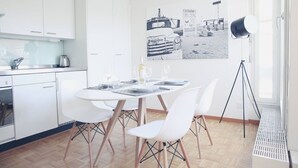 A modern kitchen with white cabinets, a dining table set for four, and a large window with a view of a building. - Charming studio in the city centre (Art 14) (Zürich)