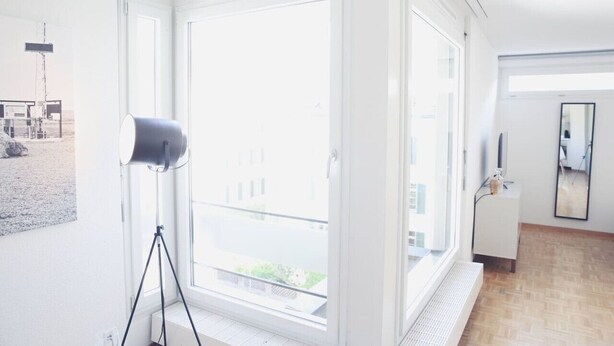 A bright room with large windows, a tripod, and a white cabinet. - Charming studio in the city centre (Art 14) (Zürich)