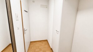 A hallway with a wooden floor, white walls, and two closed doors.