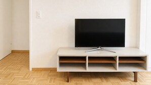 A television on a white stand with a wooden floor. - Terrific studio in the city centre (Art 9) (Zürich)