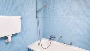 A bathroom with a white bathtub, a showerhead, and a toilet. - Charming studio in the city centre (Art 4) (Zürich)