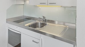 Een keuken met een RVS-spoelbak, een ingebouwde oven en een magnetron.