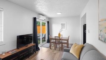 Una sala de estar moderna con televisor de pantalla plana, muebles de madera y un ventanal corredizo al exterior.