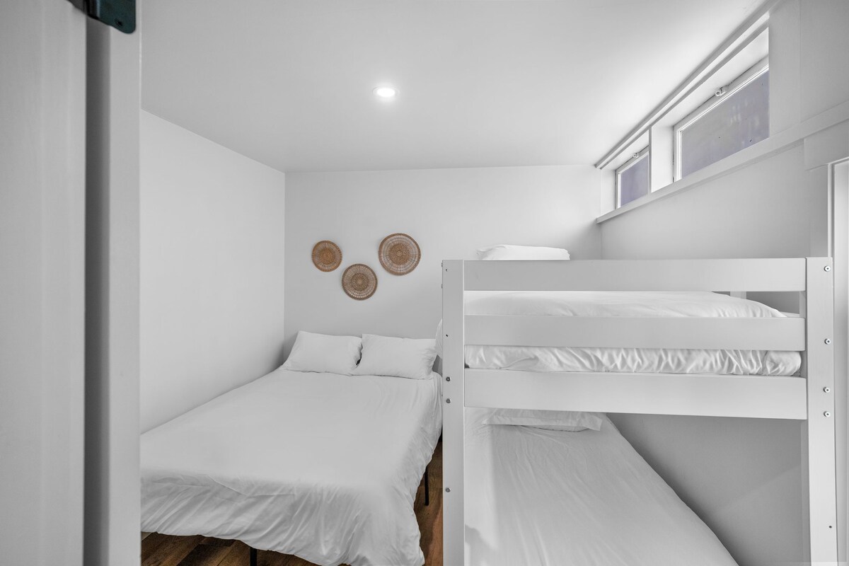 A room with bunk beds, a ceiling light, and wall decor.