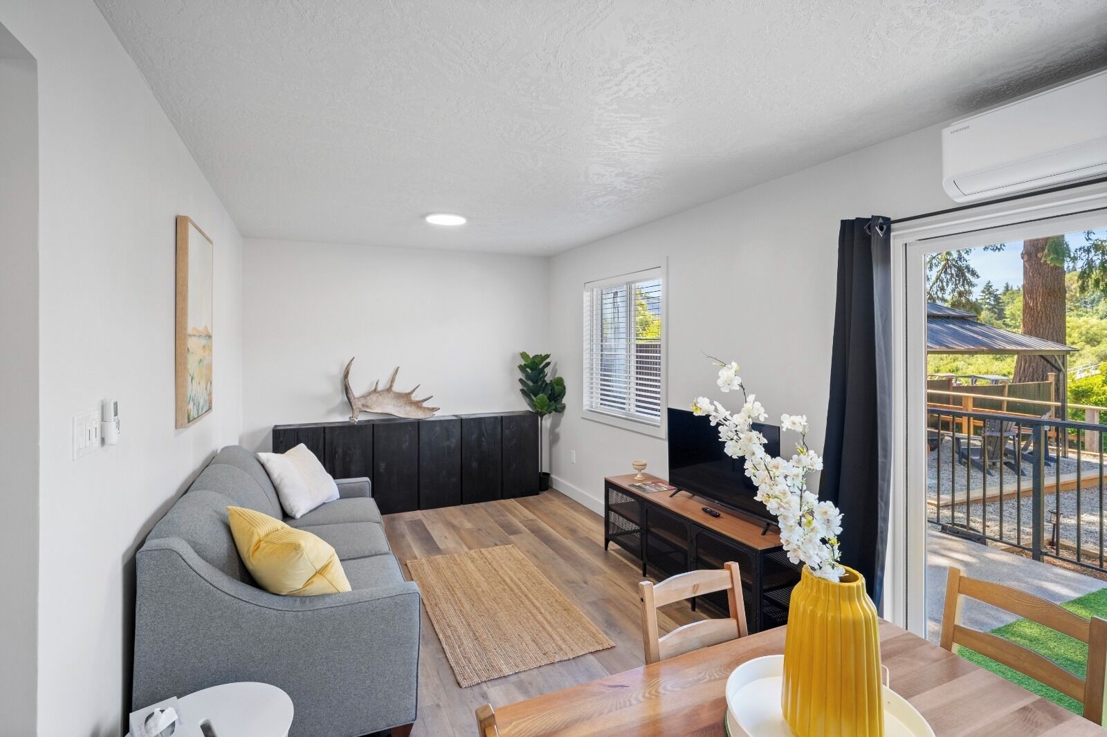 A modern living room with a grey sofa, a wooden coffee table, and a TV.