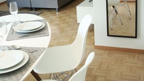 Ett modernt hotellrum med en säng, ett matbord dukat för två personer och en spegel som reflekterar rummet.