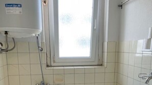 Une salle de bain comprenant des toilettes, une baignoire, une fenêtre et un lavabo.