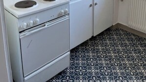 Une petite cuisine avec un poêle blanc, un évier et une fenêtre.
