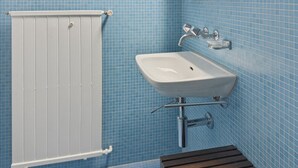 A bathroom with a white radiator, a sink, and a mirror. - Charming studio in the city centre (Art 21) (Zürich)