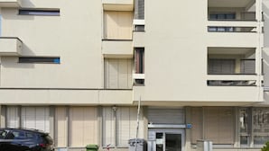 A multi-story building with a ground-level entrance, a parked car, and a bicycle. - Charming studio in the city centre (Art 21) (Zürich)