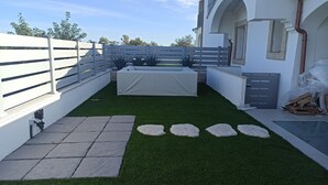 A courtyard with artificial grass, stone pathway, and a covered area. - Villa 21 - B - Two Bedroom Villa, Sleeps 4 (Budoni)