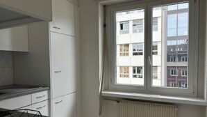 A kitchen with white cabinets, a granite countertop, and a window with a view of buildings.