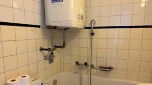 A bathroom with a bathtub, toilet, and a water heater.