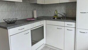 A kitchen with white cabinets, a built-in oven, a dishwasher, and a granite countertop.