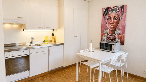 A compact kitchen with white cabinets, a microwave, and a dining table with chairs. - Practical studio in the city center (Art 7) (Zürich)