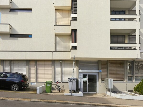 A multi-story building with a ground-level entrance, a parked car, and a bicycle.