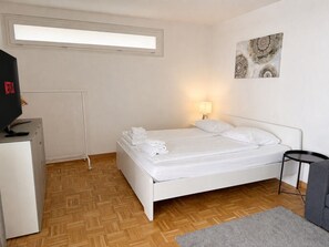 A bedroom with a bed, a desk, a lamp, and a wall-mounted artwork. - Practical studio in the city center (Art 7) (Zürich)
