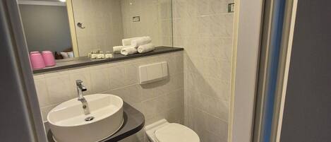 Un baño moderno con un lavabo blanco, un inodoro y un espejo.