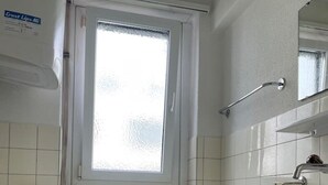 A bathroom with a bathtub, a sink, a toilet, and a window. - Practical Studio nearby Lake (Cross 6) (Zürich)