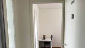 A hallway with a carpeted floor leading to a dining area with a table and chairs. - Practical Studio nearby Lake (Cross 6) (Zürich)