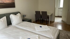 Een hotelkamer met een bed, een bureau, twee stoelen, een nachtkastje en een schilderij aan de muur.