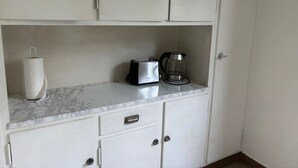 Een keuken met witte kastjes, een marmeren aanrecht, een broodrooster, een koffiezetapparaat en een papieren handdoekhouder.