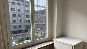 Une pièce avec une fenêtre, un radiateur et un petit meuble blanc.