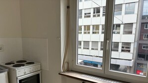Une cuisine équipée d’une cuisinière, d’un four et d’une fenêtre donnant sur un immeuble.