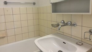 Une salle de bain avec un lavabo blanc, un miroir et un porte-serviettes.