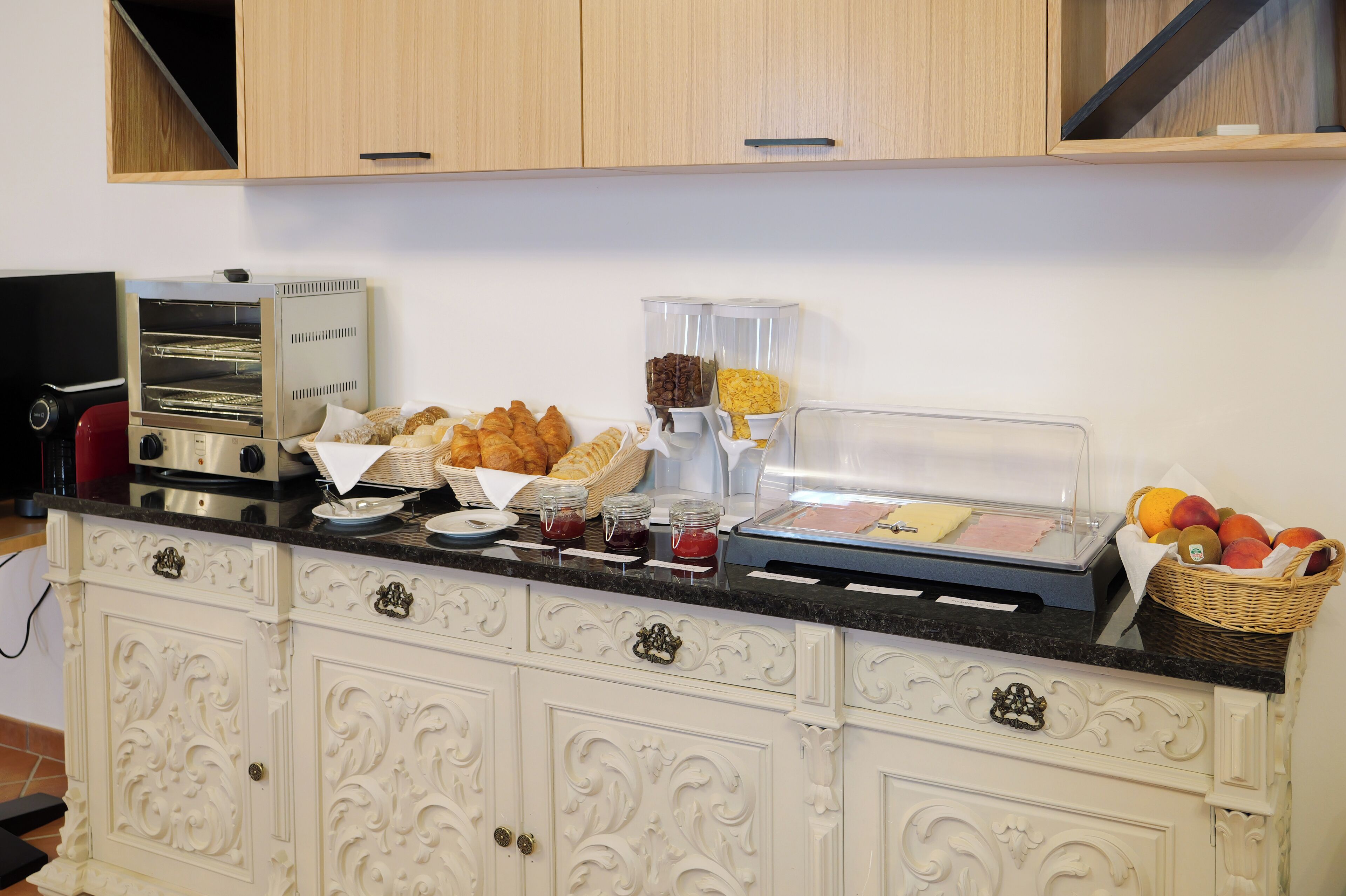 Un bufé de desayuno con horno tostador, pasteles, mermeladas y una cesta de frutas.