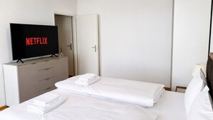 A hotel room with two beds, a TV on a dresser, and a wardrobe. - Practical and cozy City Studio (Art 6) (Zürich)