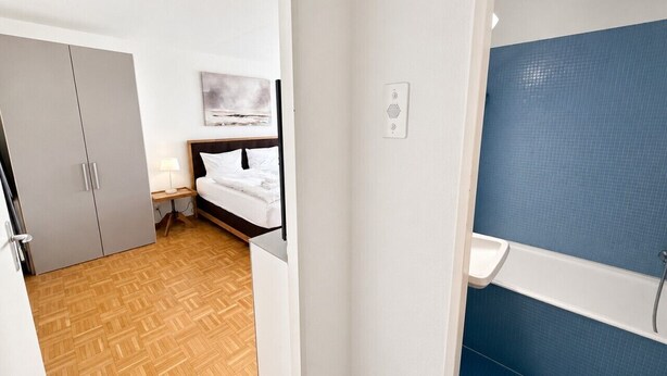 A bedroom with a bed, bedside table, and a nightstand. There is a wardrobe and a painting on the wall. - Practical and cozy City Studio (Art 6) (Zürich)