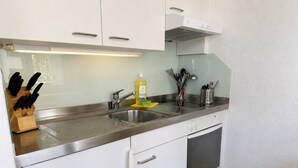 A kitchen with white cabinets, stainless steel countertops, a built-in oven, and a sink.