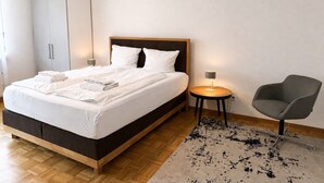 A modern bedroom with a bed, a chair, a small table, and a wardrobe.
