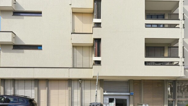 A multi-story building with a ground-level entrance, a parked car, and a bicycle.