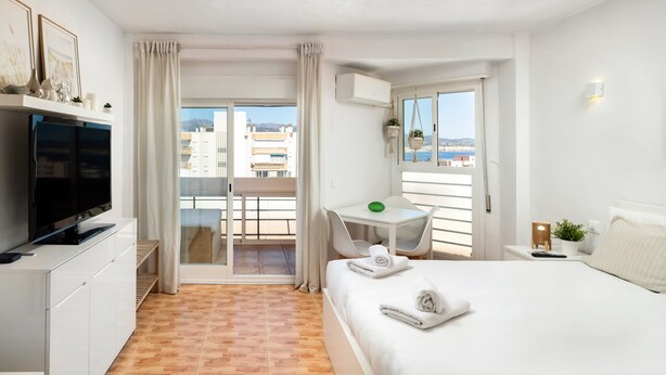 A hotel room with a bed, a TV, a desk, and a balcony with a view. - Apartment 'Plazamar 039' with Sea View, Wi-Fi and Air Conditioning (Torre del Mar)