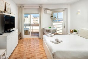 Una camera d'albergo con un letto, una TV, una scrivania e un balcone con vista.