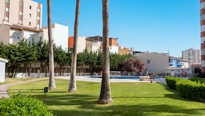 A courtyard with palm trees, a swimming pool, and buildings in the background. - Apartment 'Plazamar 039' with Sea View, Wi-Fi and Air Conditioning (Torre del Mar)