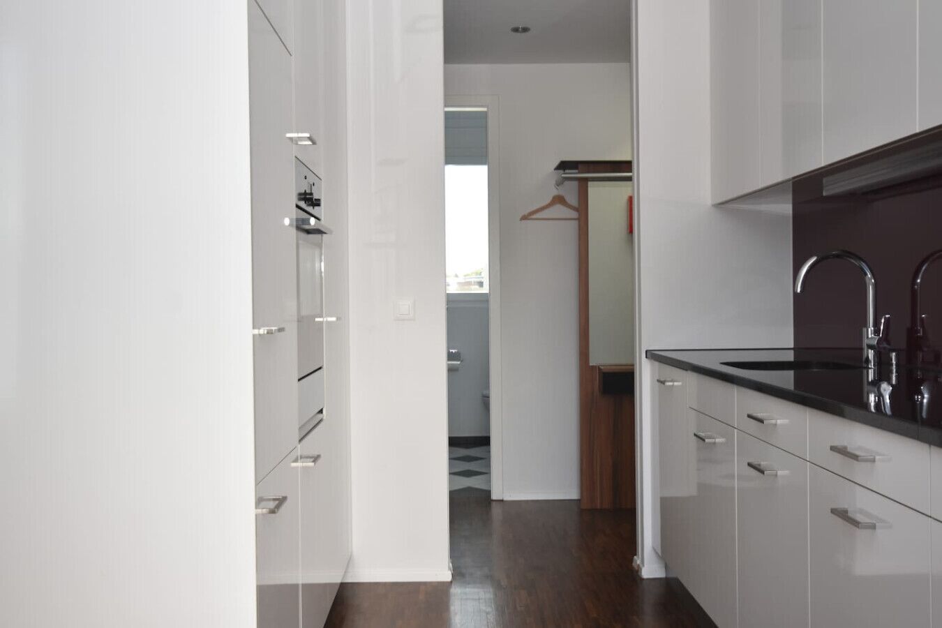 A modern kitchen with white cabinetry, a black countertop, and stainless steel appliances.