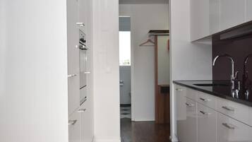 A modern kitchen with white cabinetry, a black countertop, and stainless steel appliances.