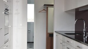 Uma cozinha moderna com armários brancos, bancada preta e piso de madeira.