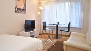 A hotel room with a bed, a TV, a small table with chairs, and a sofa. - Nice studio in the city center (Vineyard 11) (Zürich)