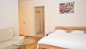 A bedroom with a bed, a glass table, a sofa, and a shower. - Nice studio in the city center (Vineyard 11) (Zürich)