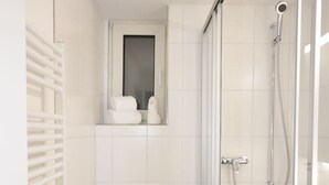 A compact bathroom with a toilet, a shower, and a towel rack.