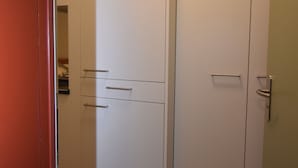 A hallway with a wooden floor, a white door with a handle, and a partially visible red door on the left.