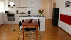 Cocina moderna con armarios blancos, una isla central con frutero, una lámpara de pie y una pared de acento roja.