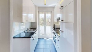 A modern kitchen with white cabinets, a black countertop, and a blue-tiled floor. - Very spacious studio / city center (Parkview 4) (Zürich)