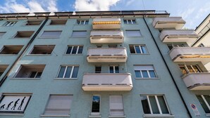 A multi-story building with balconies, windows, and a sign with a family silhouette. - Very spacious studio / city center (Parkview 4) (Zürich)